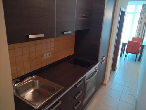 a kitchen with a stainless steel sink and a stove at Апартамент Сънсет Ризорт in Pomorie