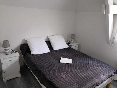 a bedroom with a bed with a book on it at Appartement fonctionnel et chaleureux proche mer in Le Croisic