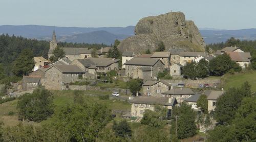 a village with a large rock in the background at le Henry in Queyrières