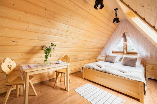 a bedroom in a log cabin with a bed and a table at Pokoje Gościnne Pod Łosiówkami in Poronin