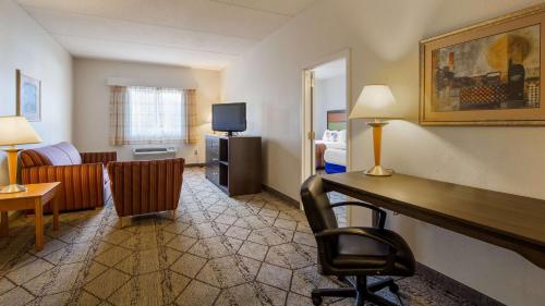 a hotel room with a desk and a living room at Best Western Plus Newport News in Newport News
