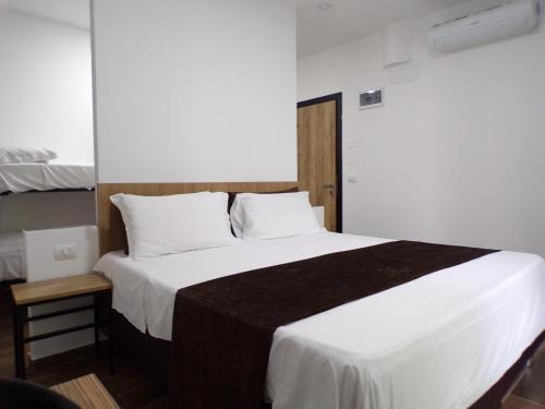 una camera da letto con un grande letto con lenzuola e cuscini bianchi di Hotel Nord Est a Riccione