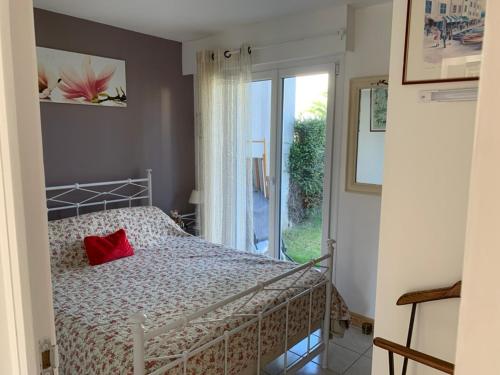 ein Schlafzimmer mit einem Bett mit einem roten Kissen darauf in der Unterkunft Résidence Les jardins de Courseulles F3 in Courseulles-sur-Mer