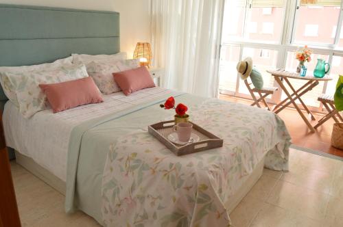 a bedroom with a bed with a tray with flowers on it at Espectacular apartment con piscina, vistas al mar y tranquilidad 10 min desde Valencia in Puebla de Farnals