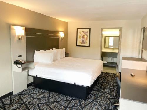 a hotel room with a large bed with white sheets at Baymont by Wyndham Dothan in Dothan