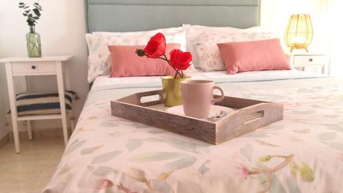 a tray with a cup and flowers on a bed at Espectacular apartment con piscina, vistas al mar y tranquilidad 10 min desde Valencia in Puebla de Farnals