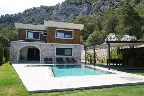 a villa with a swimming pool in front of a house at Silyan Villas in Antalya