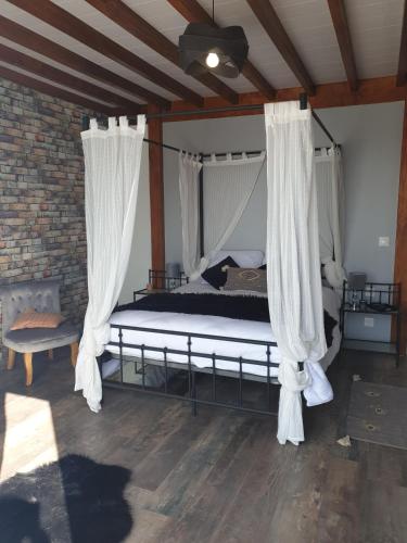 a bedroom with a canopy bed with curtains at ETCHE ARGUINIA CHAMBRES HOTES et SPA in Montory