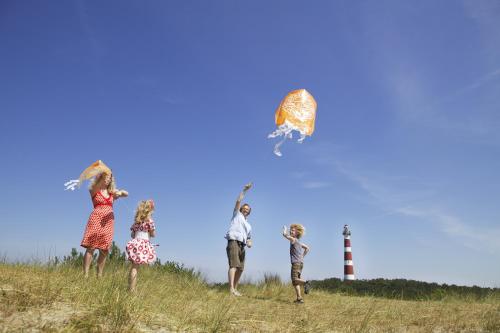 a group of children flying a kite on a hill with a lighthouse at Sier aan Zee in Hollum