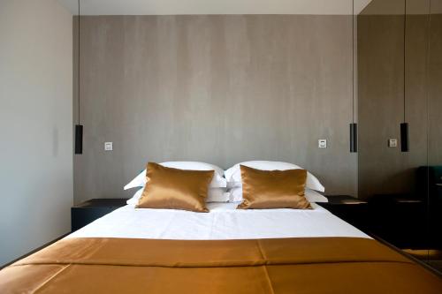 a large bed with white sheets and gold pillows at The View Luxury Residence with Pool in Zadar