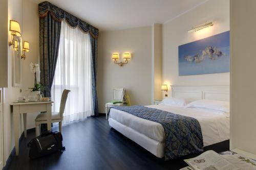 a hotel room with a large bed and a desk at Plaza Hotel Abano Terme in Abano Terme