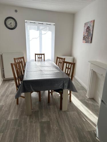 une salle à manger avec une table, des chaises et une horloge dans l'établissement Charmante maison de ville avec parking à côté., à Morlaix