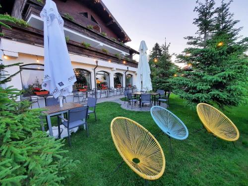 Pensiune & Restaurant Victoria في بالتينيس: مجموعة من الكراسي والطاولات مع مظلات على العشب