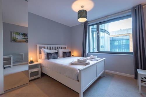 a bedroom with a white bed and a large window at Glorious 2BR APT in Maidenhead Town Centre - FREE Parking, Wi-Fi & Netflix - By JDF Property in Maidenhead