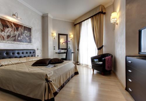 a bedroom with a bed and a chair and a television at Plaza Hotel Abano Terme in Abano Terme