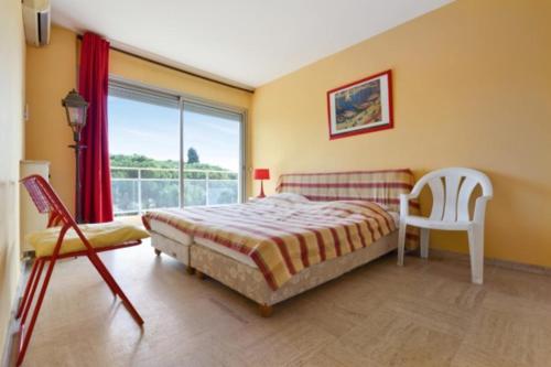 une chambre avec un lit, une chaise et une fenêtre dans l'établissement 90m proche PLAGE avec VUE MER et 2 TERRASSES !, à Cannes