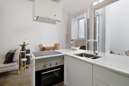 a white kitchen with a sink and a stove at Casa Vermelha ii in Faro