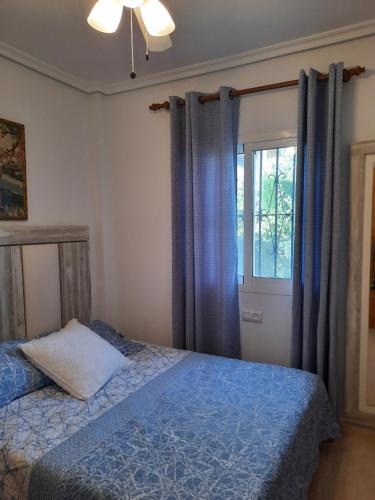 a bedroom with a bed and a window with blue curtains at Chalet adosado con piscina in Vera