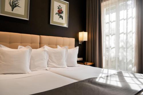 1 dormitorio con 1 cama grande con almohadas blancas y ventana en San Gil, en Sevilla