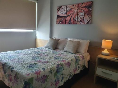 1 dormitorio con 1 cama y una pintura en la pared en Parque Olímpico da Barra, en Río de Janeiro