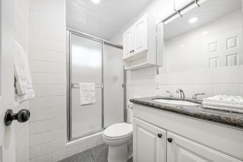 a white bathroom with a toilet and a sink at Newport Family Castle in Newport Beach