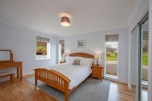 a bedroom with a bed and a desk and windows at Seabank House in Oban