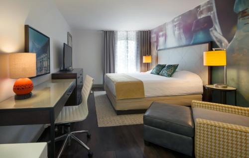 a hotel room with a bedroom with a bed and a desk at Hotel Indigo Savannah Historic District by IHG in Savannah