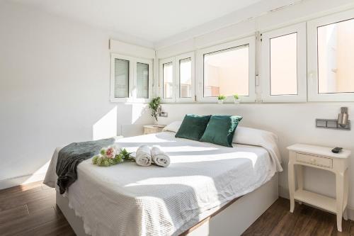 Un dormitorio blanco con una cama con toallas. en Ático Avda Cádiz Playa, en Cádiz