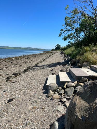 a rocky beach with two benches on it at Oakwell holiday village in Ramelton