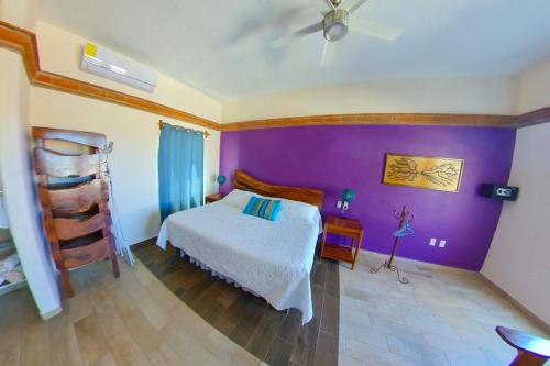 1 dormitorio con cama y pared púrpura en Villa Los Corales, en Sayulita