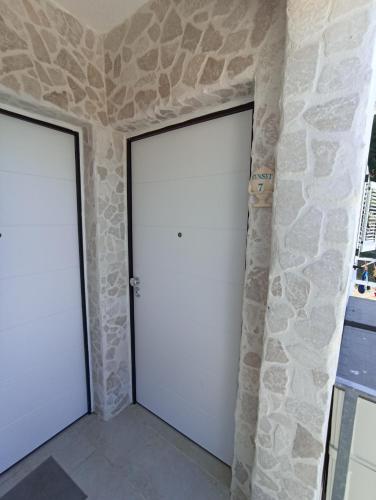 two white garage doors in a stone wall at BlueSun Apartments in Leporano Marina