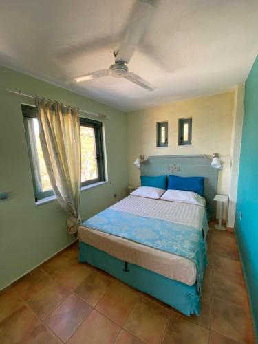 a bedroom with a blue bed and two windows at Wavefront Serenity - Exotic & Dreamy Getaway in Marmarion