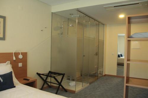 a glass shower in a bedroom with a bed at Hotel da Vila in Manteigas