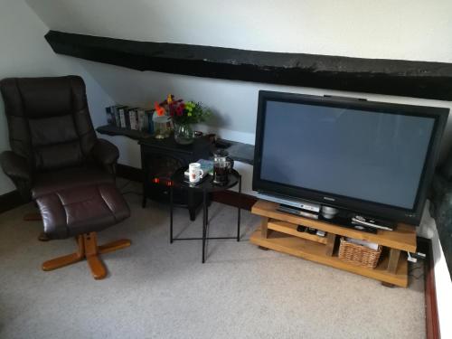 a living room with a television and a chair at Penybont Barn in Llangorse