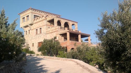 a large stone building with a road in front of it at Lesvos Tower House Komninos in Sígrion