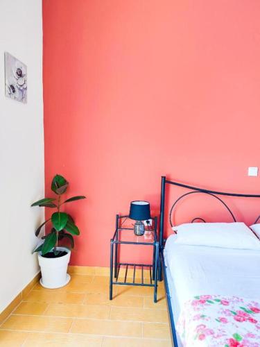 a bedroom with a red wall with a bed and a plant at Sette Isole Countryside Retreat Near Egremni Beach in Athanion