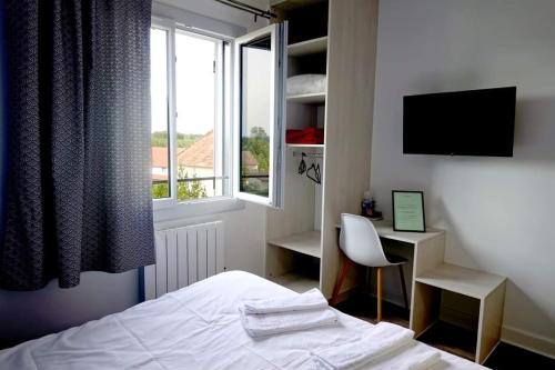 a bedroom with a bed and a desk and a window at Hotel La Grotte in Sagy