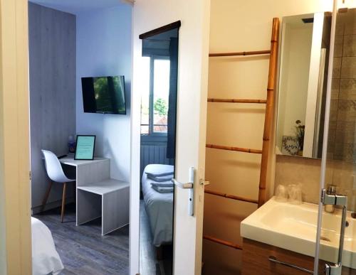 a bathroom with a sink and a desk with a computer at Hotel La Grotte in Sagy