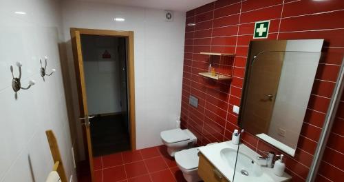 - une salle de bains en carrelage rouge avec lavabo et miroir dans l'établissement Lendas de Portugal, à Olhos de Água