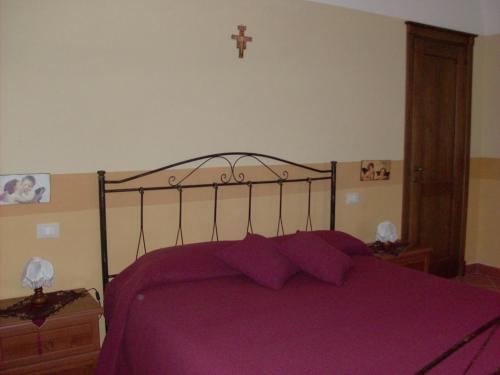 Country House Agriturismo Ciuccunit في Bucchianico: غرفة نوم مع سرير أرجواني مع صليب على الحائط