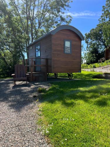 a tiny house with a bench in the grass at Oakwell holiday village in Ramelton