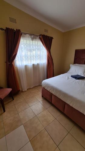 a bedroom with a bed and a window at Stone Villa in Gaborone