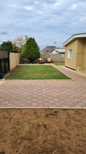 Una pasarela de ladrillo en un patio junto a una casa en Stone Villa, en Gaborone