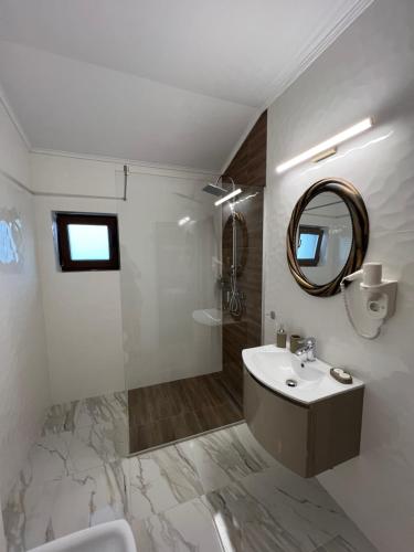 a white bathroom with a sink and a mirror at Pensiunea Izora in Crisan