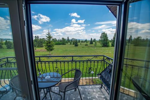 a balcony with a table and chairs and a view of a field at Hotel Perła Dunajca in Czarny Dunajec