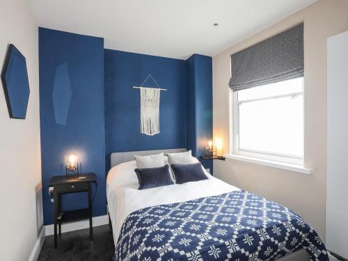 a blue bedroom with a bed and a window at Cwm Gwyrfai in Caernarfon