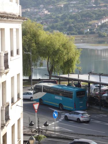 a blue bus driving down a city street with cars at O Abeiro do Eume in Puentedeume