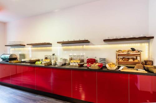 a kitchen with a red counter with bread and pastries at Hotel Frechener Hof in Frechen