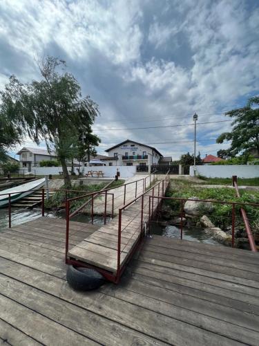 un paseo marítimo de madera con un banco encima en Pensiunea Izora en Crisan