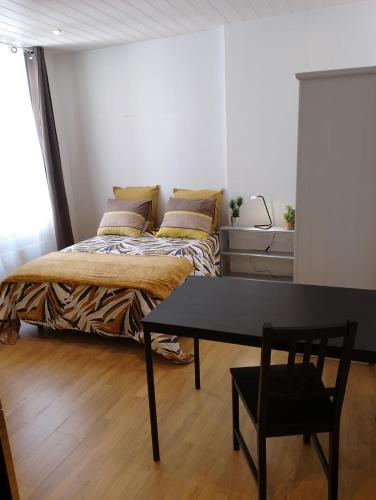 une chambre avec un lit et une table dedans dans l'établissement Le Carnot, à deux pas du centre ville, à Besançon